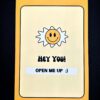 Yellow card with smiley sun and text.