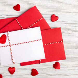 Red envelopes and hearts on wood.