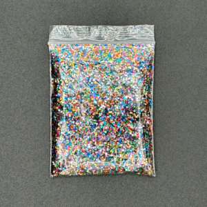 Bag of colorful glitter on gray surface.