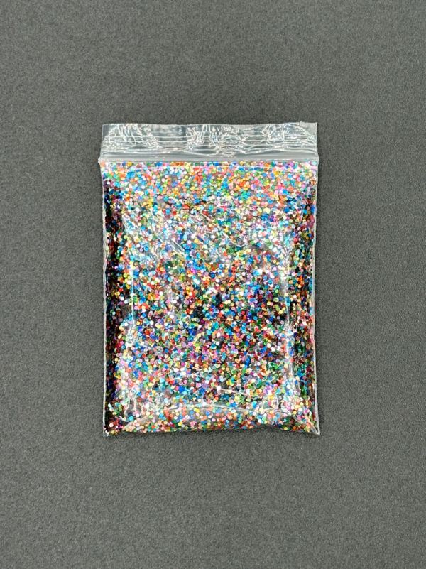 Bag of colorful glitter on gray surface.